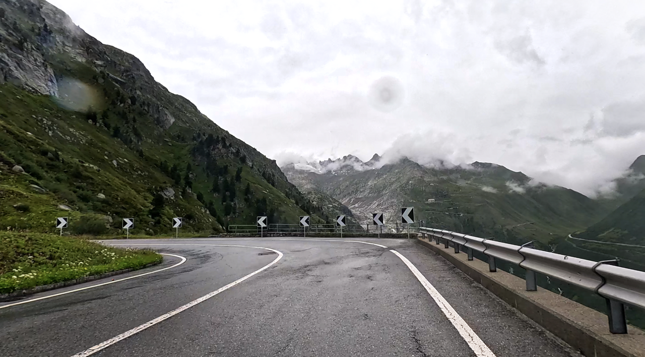 Eine Kehre der Auffahrt zum Grimselpass bietet die Möglichkeit, kurz anzuhalten, und einen Blick auf den Furkapass, den Rhône-Gletscher und das berühmte Hotel Belvedérè zu riskieren.