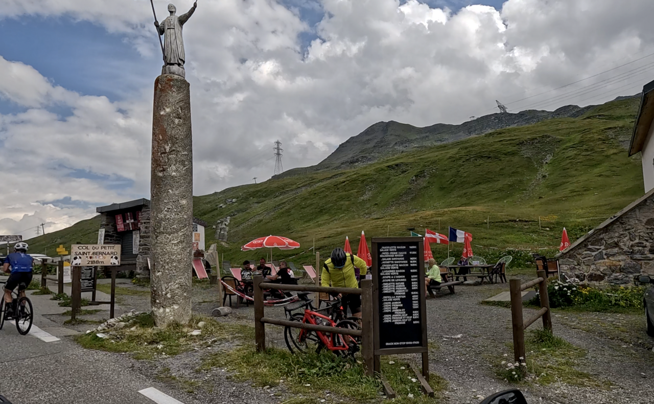 Auch auf der Passhöhe, auf der italienischen Seite steht eine Statue. Das Passschild dagegen ist ungewöhnlich schlicht.